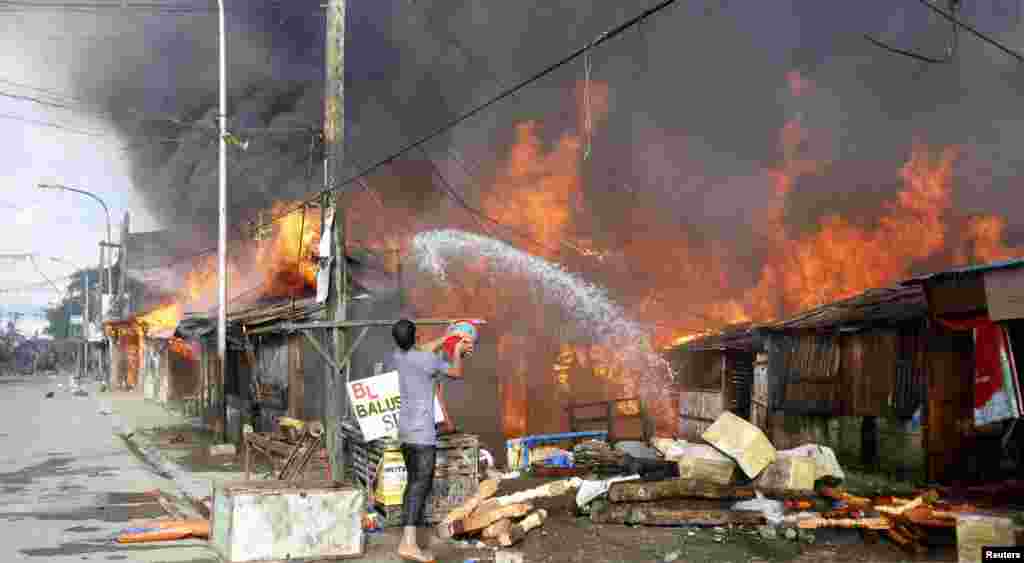 Seorang pria menyiramkan air ke sebuah rumah yang terbakar di Zamboanga, FIlipinan (12/9).