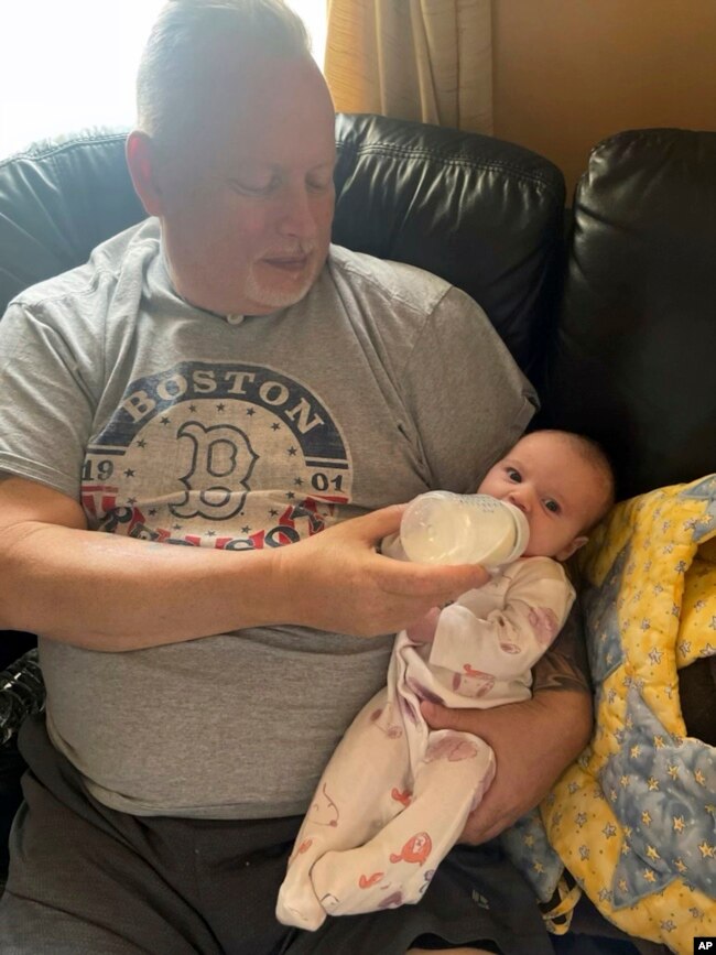 In this photo provided by the family, Marty Kedian holds his granddaughter in Pelham, N.H., on Feb. 26, 2023, before his larynx transplant. (Family photo via AP)