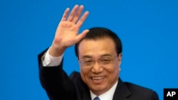 FILE - Then Chinese Premier Li Keqiang waves during a press conference after the closing session of the National People's Congress in Beijing's Great Hall of the People on March 15, 2019.