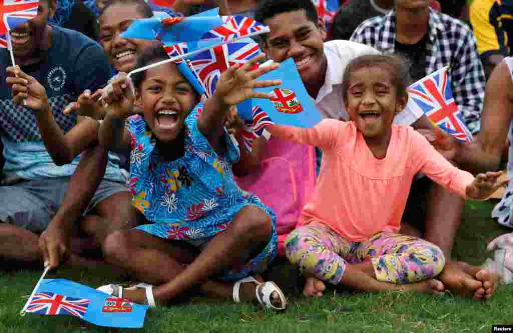Children wave flags as Britain&#39;s Prince Harry and Meghan, Duchess of Sussex, arrive in Suva, Fiji.