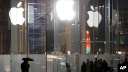 FILE - Pedestrians pass the Apple store location on Fifth Avenue in New York, June 6, 2013. 