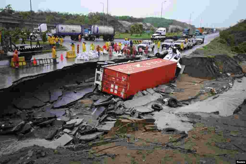 Emergency responders stand near an overturned truck after a road was washed away by floodwaters in Boca del Rio, on the outskirts of Veracruz, Mexico, June 7, 2014.