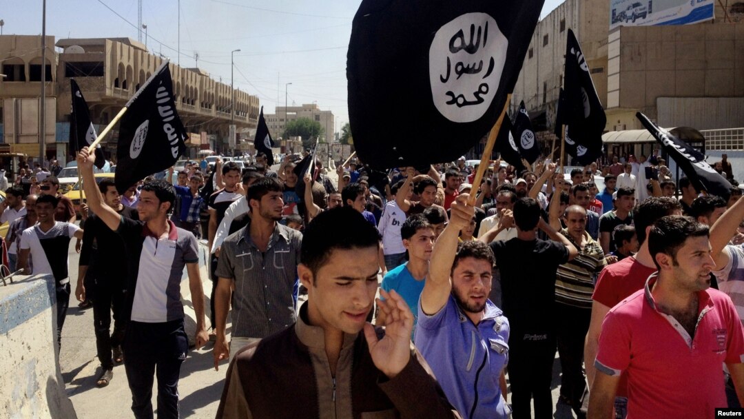 FILE - Demonstrators chant pro-Islamic State group slogans as they wave the group's flags in front of the provincial government headquarters in Mosul, Iraq, June 2014.