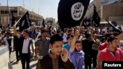 FILE - Demonstrators chant pro-Islamic State group slogans as they wave the group's flags in front of the provincial government headquarters in Mosul, Iraq, June 2014.