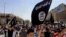 File - Demonstrators chant pro-Islamic State group slogans as they wave the group's flags in front of the provincial government headquarters in Mosul, Iraq, June 2014.