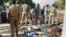 Policemen and relatives stand near the victims of a massive blaze swept that through the Om Siva Shakti fireworks factory in Sivakasi, India on Sept. 5, 2012. 