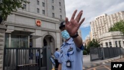 當押送任志強的警車抵達北京第二中級人民法院時一名警察在向記者做手式。 （2020年9月11日）