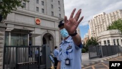 當押送任志強的警車抵達北京第二中級人民法院時一名警察在向記者做手式。 （2020年9月11日）