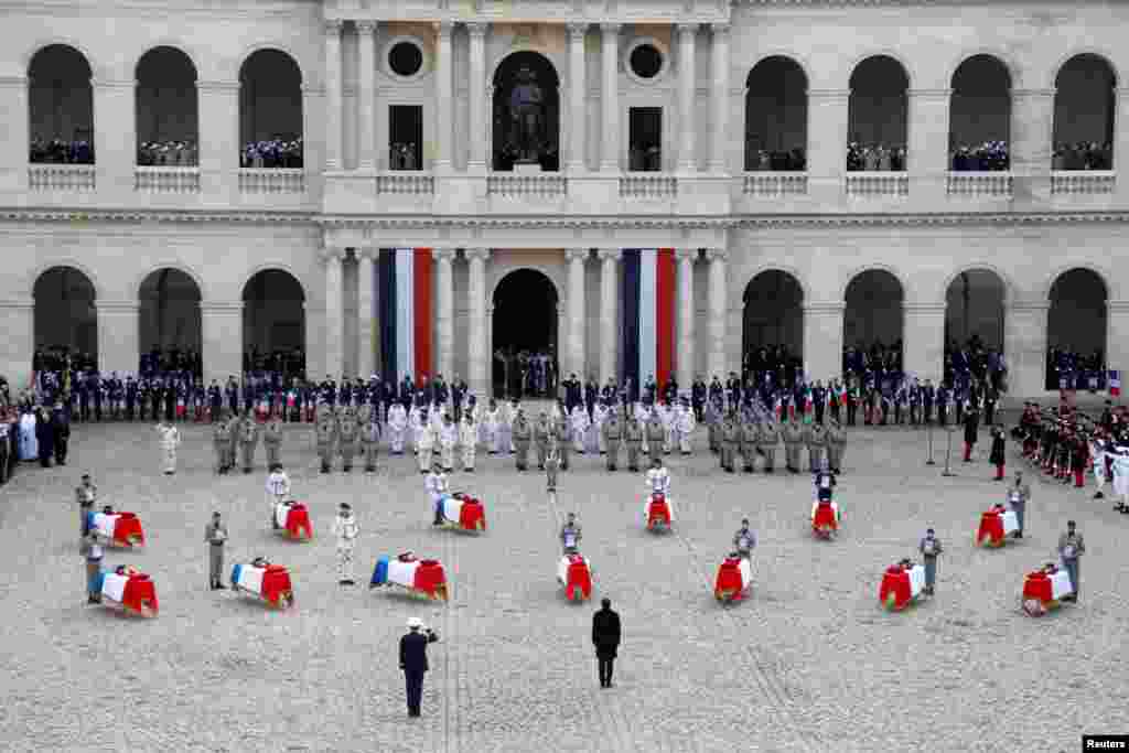  French President Emmanuel Macron pays his respect to the thirteen French soldiers killed in Mali, in front of the flag-draped coffins, during a ceremony at the Hotel National des Invalides in Paris.