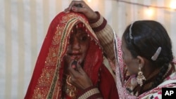 Seorang perempuan memberi hiasan wajah kepada calon pengantin Hindu sebelum pernikahannya di Karachi, Pakistan (foto: ilustrasi). Pakistan meloloskan UU baru untuk melindungi hak perkawinan masyarakat minoritas Hindu.