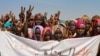 FILE: Sudanese internally displaced people hold a banner as they stage a sit in to protest the end of the mandate of the United Nations and African Union peacekeeping mission (UNAMID), in Kalma camp in Nyala, the capital of South Darfur. Taken 12.31.2020