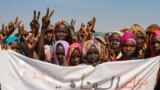 FILE: Sudanese internally displaced people hold a banner as they stage a sit in to protest the end of the mandate of the United Nations and African Union peacekeeping mission (UNAMID), in Kalma camp in Nyala, the capital of South Darfur. Taken 12.31.2020