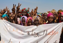 Sudanese internally displaced people hold a banner as they stage a sit in to protest the end of the mandate of the United Nations and African Union peacekeeping mission (UNAMID), in Kalma camp in Nyala, the capital of South Darfur, Dec. 31, 2020.
