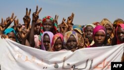 FILE: Sudanese internally displaced people hold a banner as they stage a sit in to protest the end of the mandate of the United Nations and African Union peacekeeping mission (UNAMID), in Kalma camp in Nyala, the capital of South Darfur. Taken 12.31.2020