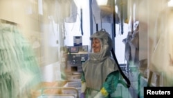 A biologist at the French-Austrian biotech firm Valneva waits in a double door system before entering a laboratory to work on an inactivated whole-virus vaccine against COVID-19 in Vienna, Austria.