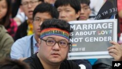 FILE - A supporter of LGBT and human rights holds a slogan during a rally supporting a proposal to allow same-sex marriage in Taipei, Taiwan, Dec. 10, 2016. Taiwanese legislators are scheduled to decide Friday on legalizing same-sex marriage, marking a potential first in Asia. 