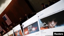 FILE - Examples of Facebook pages are seen as executives appear before the House Intelligence Committee to answer questions related to Russian use of social media to influence U.S. elections, on Capitol Hill in Washington, Nov. 1, 2017. 