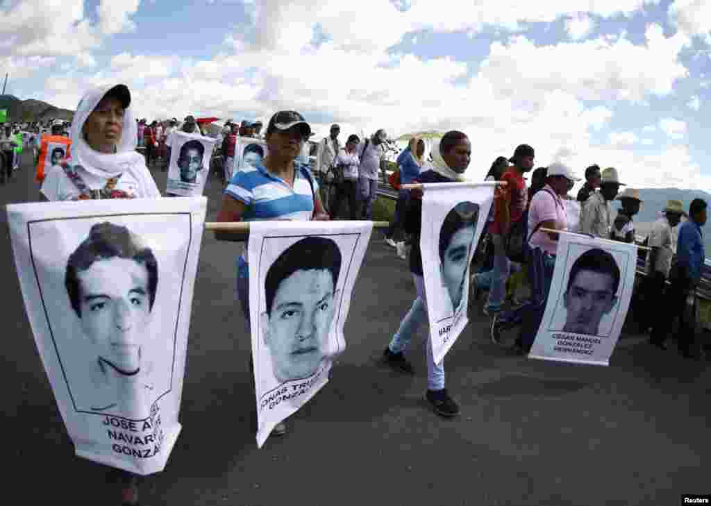 People hold posters with pictures of the 43 missing students during a demonstration along Tixtla road in Chilpancingo, Oct. 23, 2014.