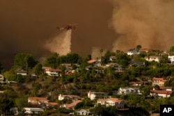 Aircraft fight the Palisades Fire as the blaze advances in Mandeville Canyon in Los Angeles, Jan. 11, 2025.