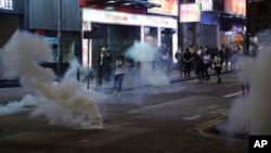 Demonstran anti pemerintah berlarian untuk menghindari gas air mata, dalam aksi protes di Hong Kong hari Minggu (27/10). 