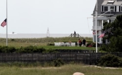 American flags are lowered as people gather at the Kennedy compound on Friday, Aug. 2, 2019, in Hyannis Port, Mass. Saoirse Kennedy Hill, granddaughter of Ethel Kennedy and her late husband Robert F. Kennedy, died at the compound Thursday…