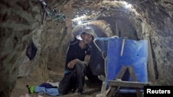 A Palestinian man calls on smugglers as he works inside a smuggling tunnel beneath the Gaza-Egypt border in Rafah in the southern Gaza Strip, June 24, 2013.