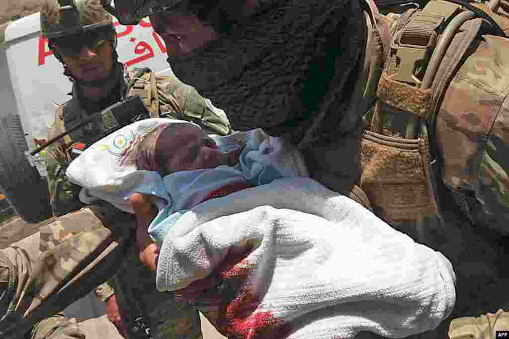 An Afghan security personnel carries a newborn baby from a hospital, at the site of an attack in Kabul, May 12, 2020.