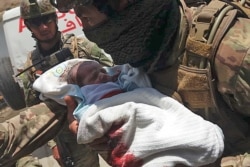 An Afghan security personnel carries a newborn baby from a hospital, at the site of an attack in Kabul, May 12, 2020.
