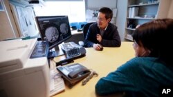 FILE - Patient Alison Cairnes (foreground) looks at images with her doctor Shumei Kato at the University of California San Diego in San Diego, Aug. 15, 2017. 