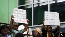 People hold up messages during a speech by Charles Gladstone, a descendant of former plantation owner John Gladstone, as he delivers an apology on behalf of the Gladstone family at Georgetown University in Georgetown, Guyana, Friday, Aug. 25, 2023.