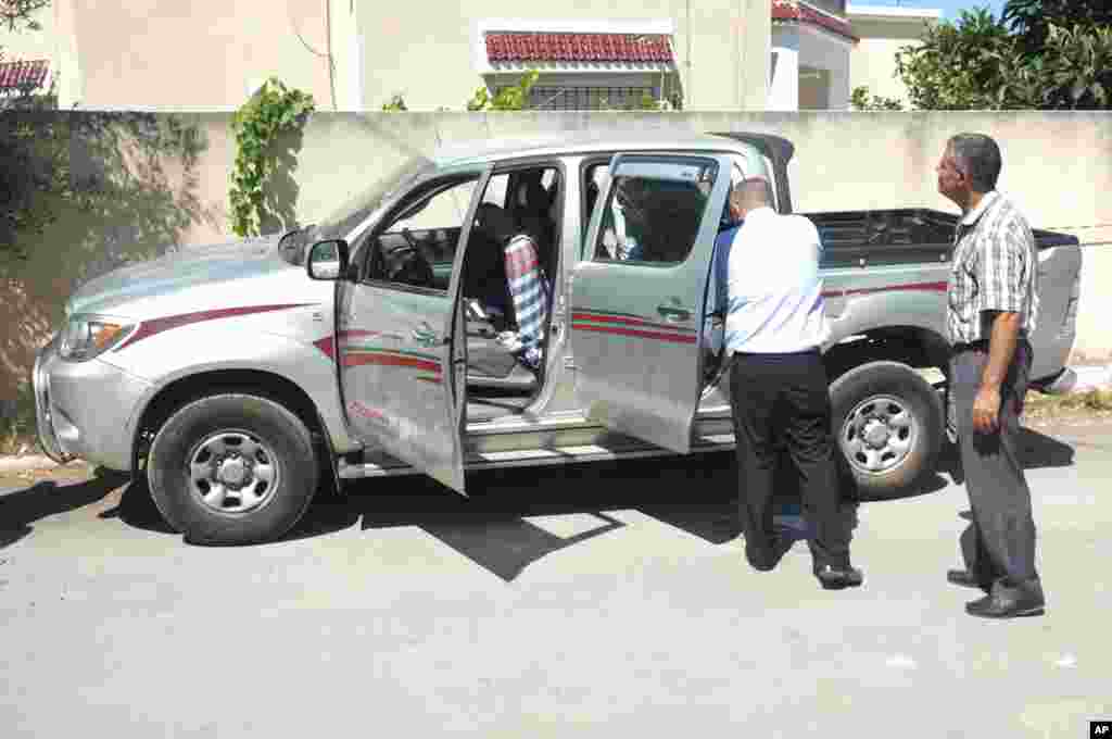 Tunisian police officers inspect Mohammed Brahmi's car in which he was shot to death outside his home in Tunis, Tunisia, Thursday, July 25, 2013. Brahmi, 58, of an Arab nationalist political party was in his car when gunmen fired several shots at him, sa