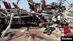 A security official collects evidence near the remains of a damaged vehicle at the site of a bomb blast in Quetta, May 23, 2013.