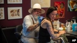 FILE - Henk Schiffmacher's needle whirrs as he tattoos the lines of am elephant on Lilian Rachmaran's back in Amsterdam, Monday, June 19, 2023. (AP Photo/Peter Dejong)