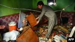 A Pakistani resident inspects a damaged television at a network office following an overnight bomb blast in Karachi, March 15, 2013.