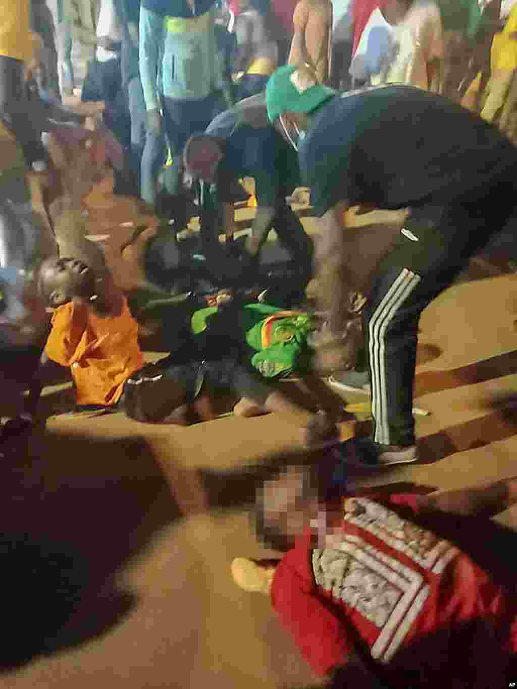 People assist victims of a stampede outside a stadium hosting a soccer game in Yaounde, Cameroon, Jan. 24, 2022. Several people have died as crowds struggled to get access to the stadium to watch the host country play Comoros.