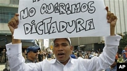 A demonstrator holds up a poster that reads in Spanish 'We don't want a dictatorship' during a demonstration outside the National Assembly building in Caracas, Venezuela, after Venezuelan President Hugo Chavez asked Congress Tuesday to grant him special p