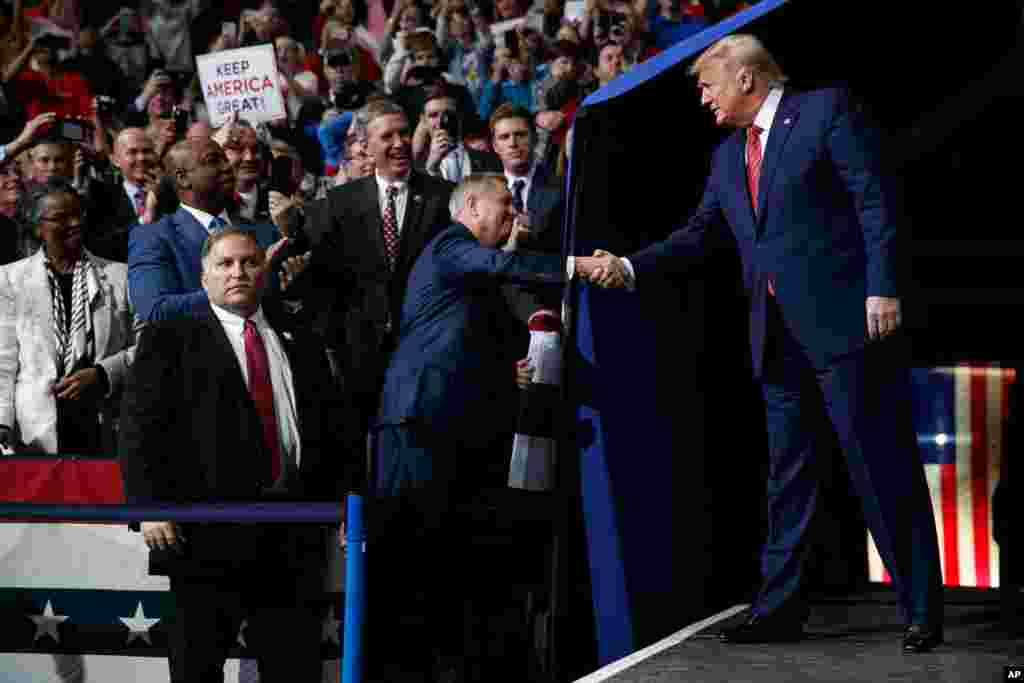 President Donald Trump shakes hands with Sen. Lindsey Graham, R-S.C., next to Sen. Tim Scott, R-S.C., as Trump arrives at a campaign rally in North Charleston, S.C., Feb. 28, 2020. 