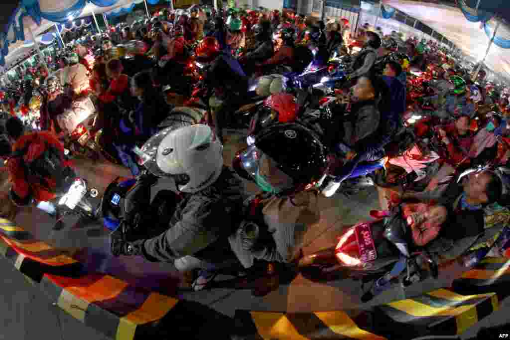 Para pengendara motor memasuki feri di pelabuhan Merak, Cilegon, Bantent untuk menyeberang ke Sumatra, 1 Juni 2019. (Foto: AFP)