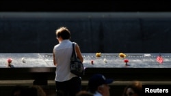 FILE - Guests looks at the memorial during the ceremony marking the 15th anniversary of the attacks on the World Trade Center at The National September 11 Memorial and Museum in Lower Manhattan in New York City, Sept. 11, 2016. 