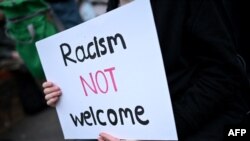 A protester holds a placard during a counter demonstration against an anti-immigration protest called by far-right activists, outside the Asylum Welcome immigration support service offices in Oxford, western England on Aug. 7, 2024.