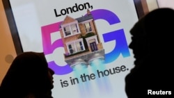 Dua warga Inggris melewati iklan jaringan 5G di sebuah toko ponsel di London (foto: ilustrasi). 