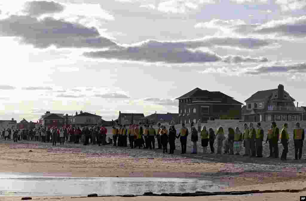 Warga berbaris sepanjang pantai di pelabuhan Belle Harbor, New York, dalam peringatan satu tahun Badai Sandy (27/10) yang diberi tema "Rockaway Rising: Hands Across the Sand." (AP/Kathy Willens)