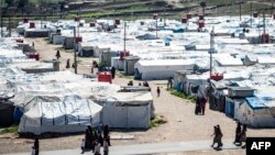 FILE - Women and children walk at Roj camp, where relatives of people suspected of belonging to the Islamic State group are held, in the countryside near al-Malikiyah in Syria's northeastern Hasakah province, March 28, 2021.