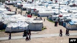 FILE - Women and children walk at Roj camp, where relatives of people suspected of belonging to the Islamic State group are held, in the countryside near al-Malikiyah in Syria's northeastern Hasakah province, on March 28, 2021.