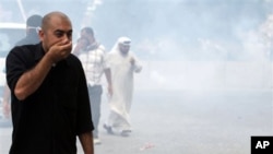 An anti-government protester reacts to clouds of tear gas fired by police in Manama, Bahrain, March 13, 2011