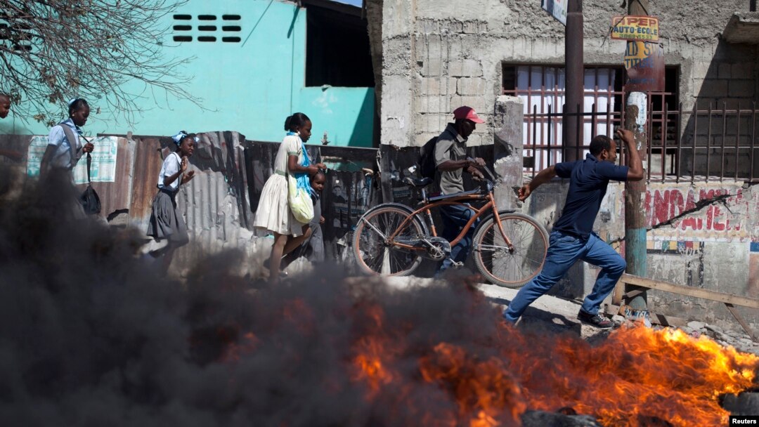 Wargamelewati barikade yang dibakar dalam protes-protes di Croix des Bouquets di pinggiran kota Port-au-Prince, Hairi (2/2). (Reuters/Andres Martinez Casares)