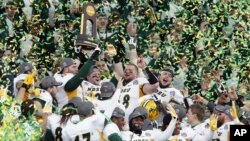 FILE - In this Jan. 10, 2015, file photo, members of the North Dakota State football team hold the championship trophy after their 29-27 win over Illinois State in the FCS Championship NCAA college football game in Frisco, Texas. 