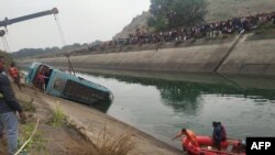 Warga berdiri di sepanjang kanal menyaksikan tim penyelamat melakukan pencarian korban bus yang jatuh ke kanal, di distrik Sidhi, negara bagian Madhya Pradesh, 16 Februari 2021. (Foto: Uma Shankar MISHRA / AFP).