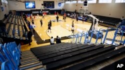 Yeshiva University players, foreground, warm up in a mostly empty Goldfarb Gymnasium at Johns Hopkins University before playing against Worcester Polytechnic Institute in a first-round game at the men's Division III NCAA college basketball tournament, Fri