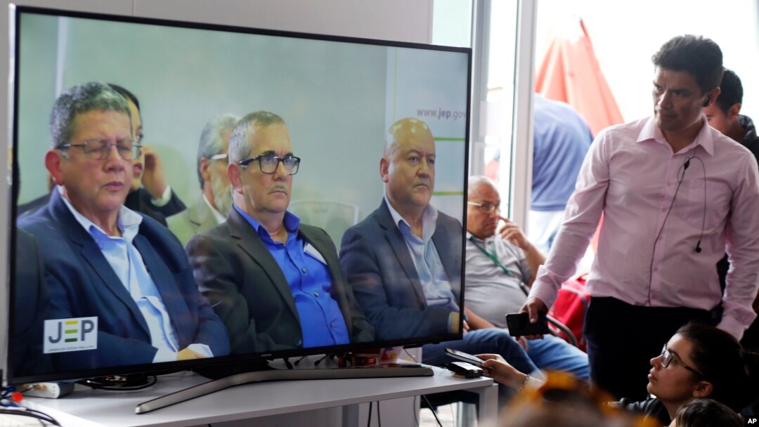 Former leaders of the Revolutionary Armed Forces of Colombia, FARC, Pablo Catatumbo, from left, Rodrigo London, and Carlos Antonio Lozada, are seen on a monitor, during a hearing of the peace tribunal in Bogota, Colombia, July 13, 2018. The FARC leaders have been summoned to the newly created special peace tribunal to respond to war crimes committed during the country's bloody five-decade conflict.